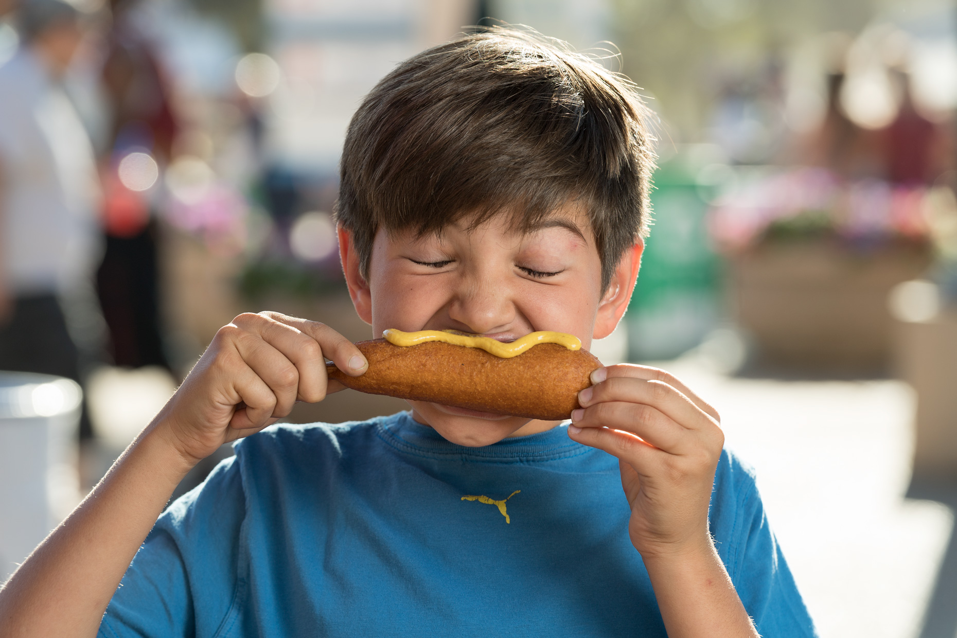 Boy enjoys corny dog at The State Fair of Texas. Photography by Kevin Brown